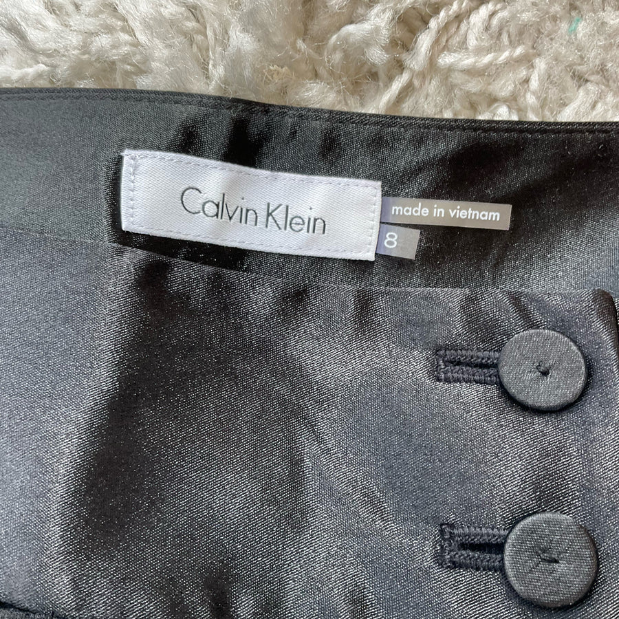Calvin Klein black pre-owned ladies pants size 8 displayed on a flat surface, showcasing fabric texture and design.
