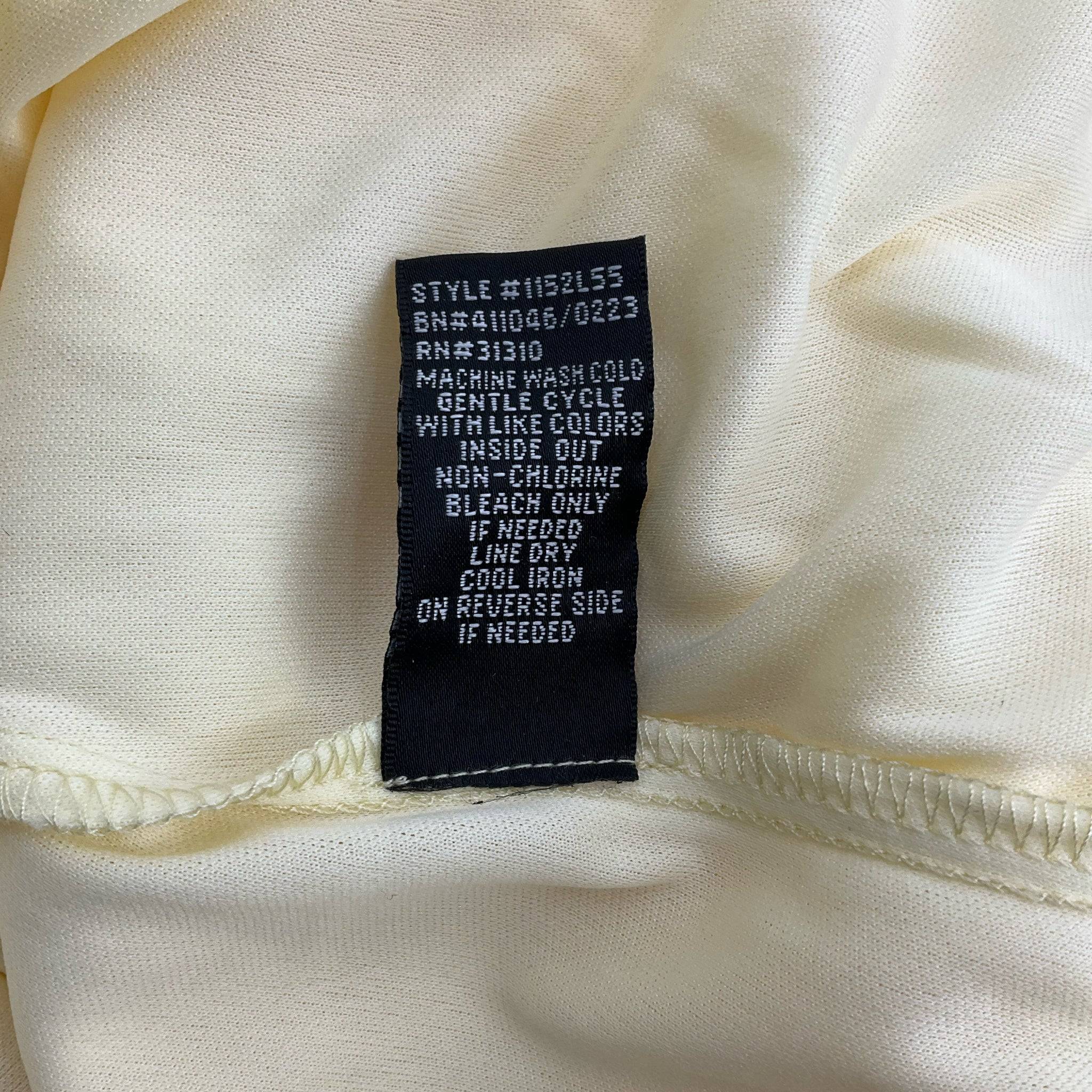Close-up of care label on BCX Spaghetti Strap Mini Dress Size Large showing washing instructions and fabric care details.