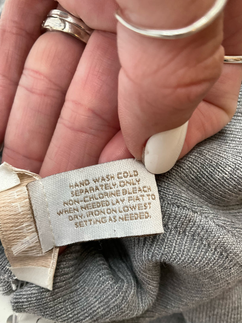 Care label of Chico's gray silk blend sweater shell, recommending hand wash cold and low iron for garment maintenance.