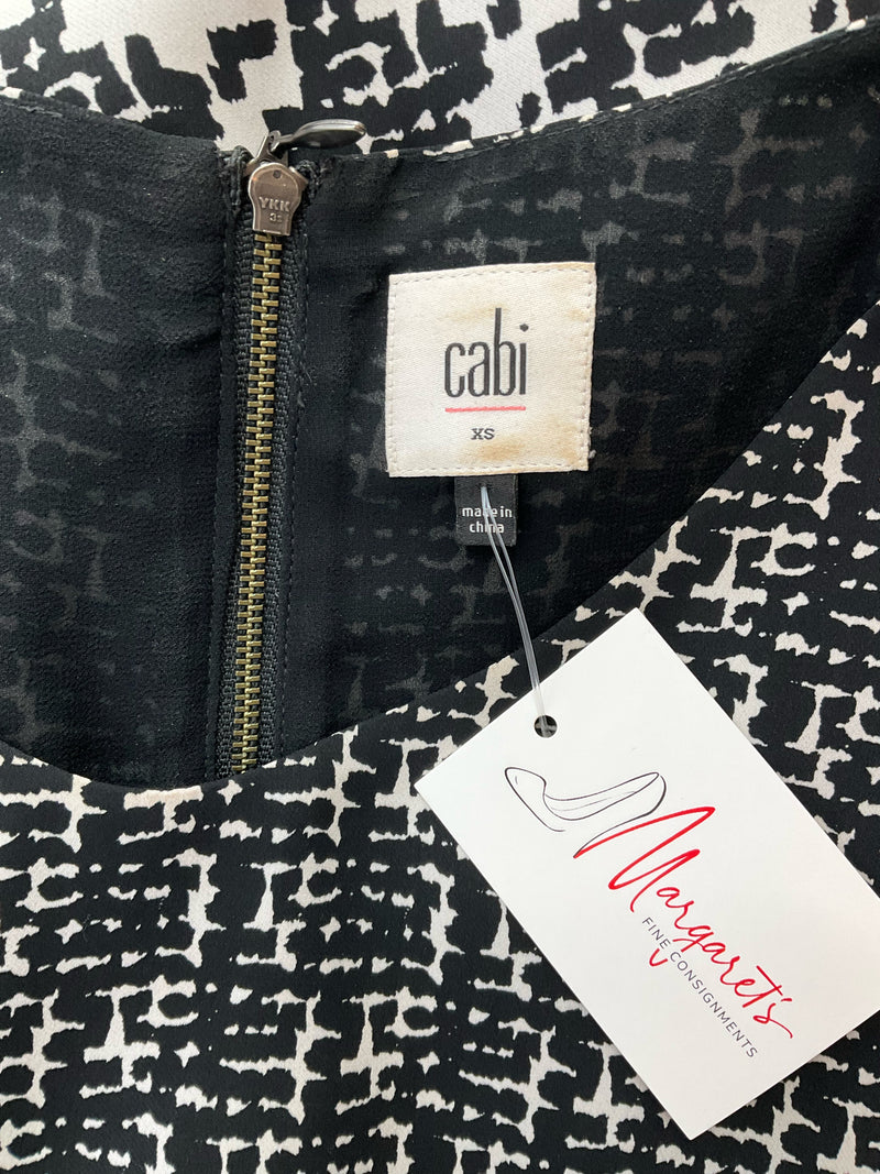 Close-up of Cabi Pixel Houndstooth Tank Top label showing size XS and zipper detail, confirming authenticity and brand tag.