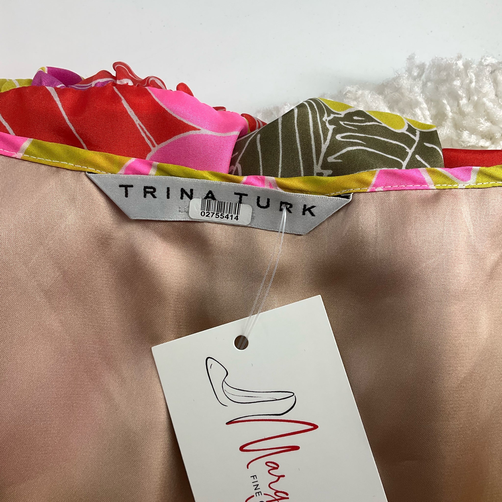Close-up of Trina Turk brand label on the Orange/Green/Purple Floral Dress - Size Large, confirming authenticity, pre-owned item.