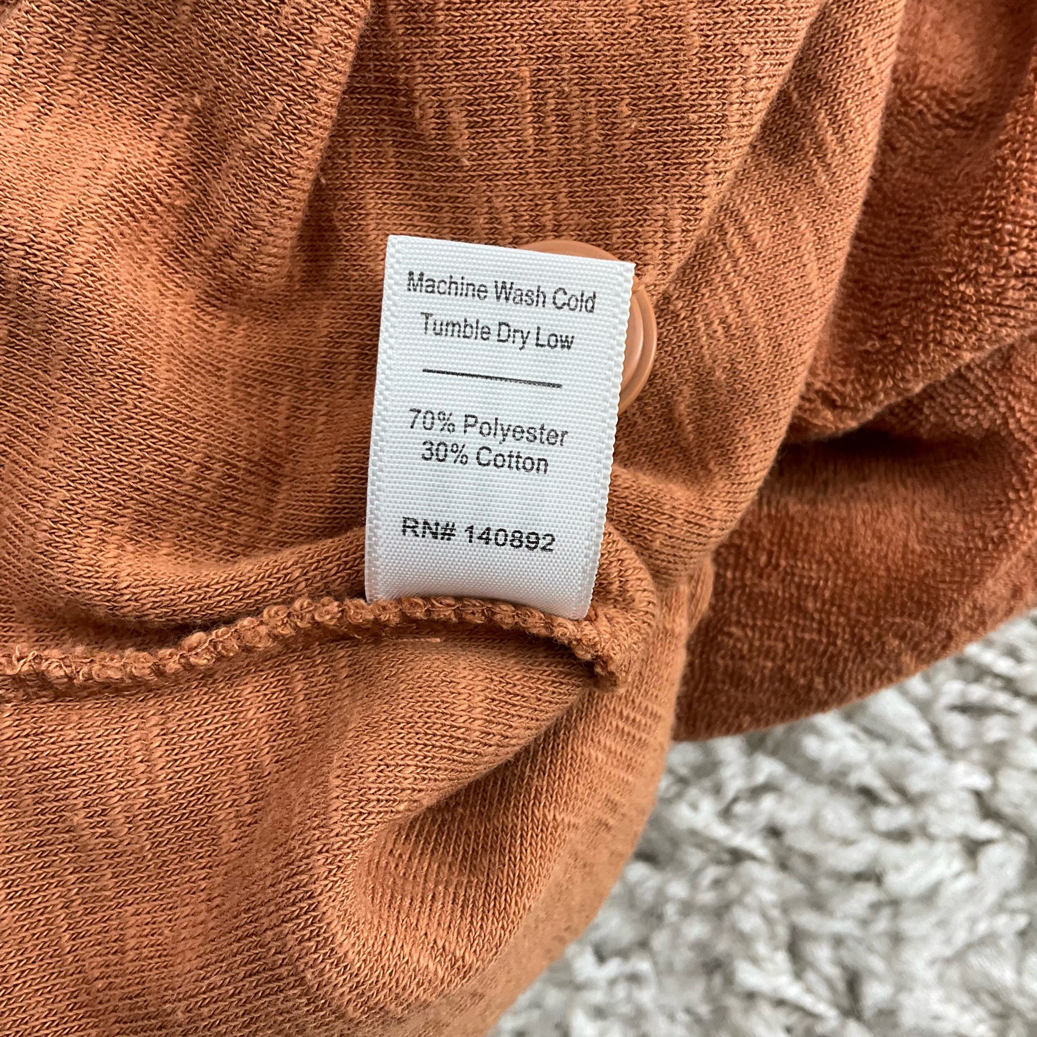 Fabric content tag of Marine Layer Rust 2 Piece Set Size Medium showing 70% polyester and 30% cotton blend with care instructions.
