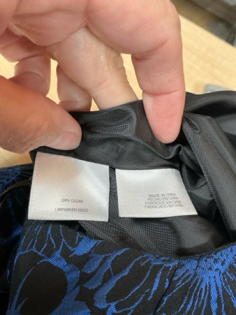 Close-up of care label on Anne Klein floral dress, indicating dry clean only instructions and fabric details for proper garment maintenance.