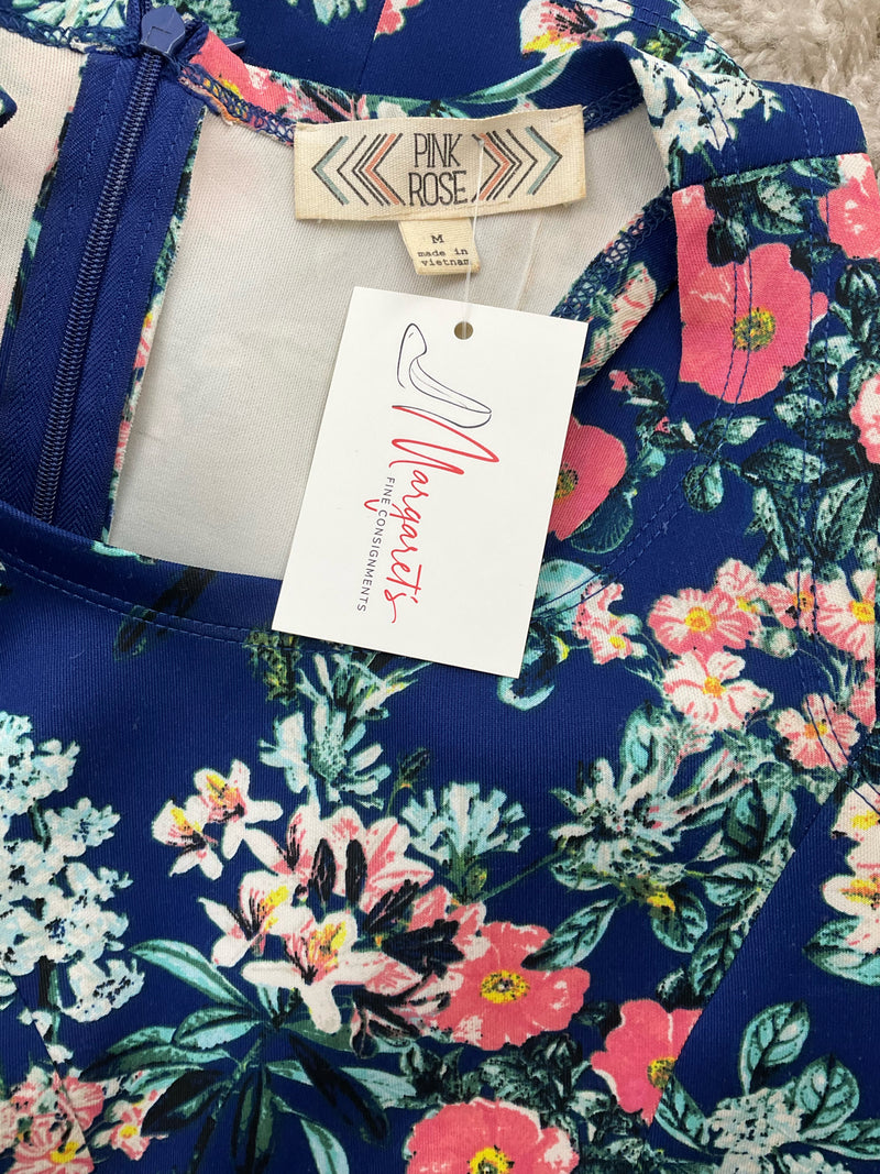 Close-up of Pink Rose dress neckline and tag, showing floral pattern and attached resale tag, size medium, pre-owned.