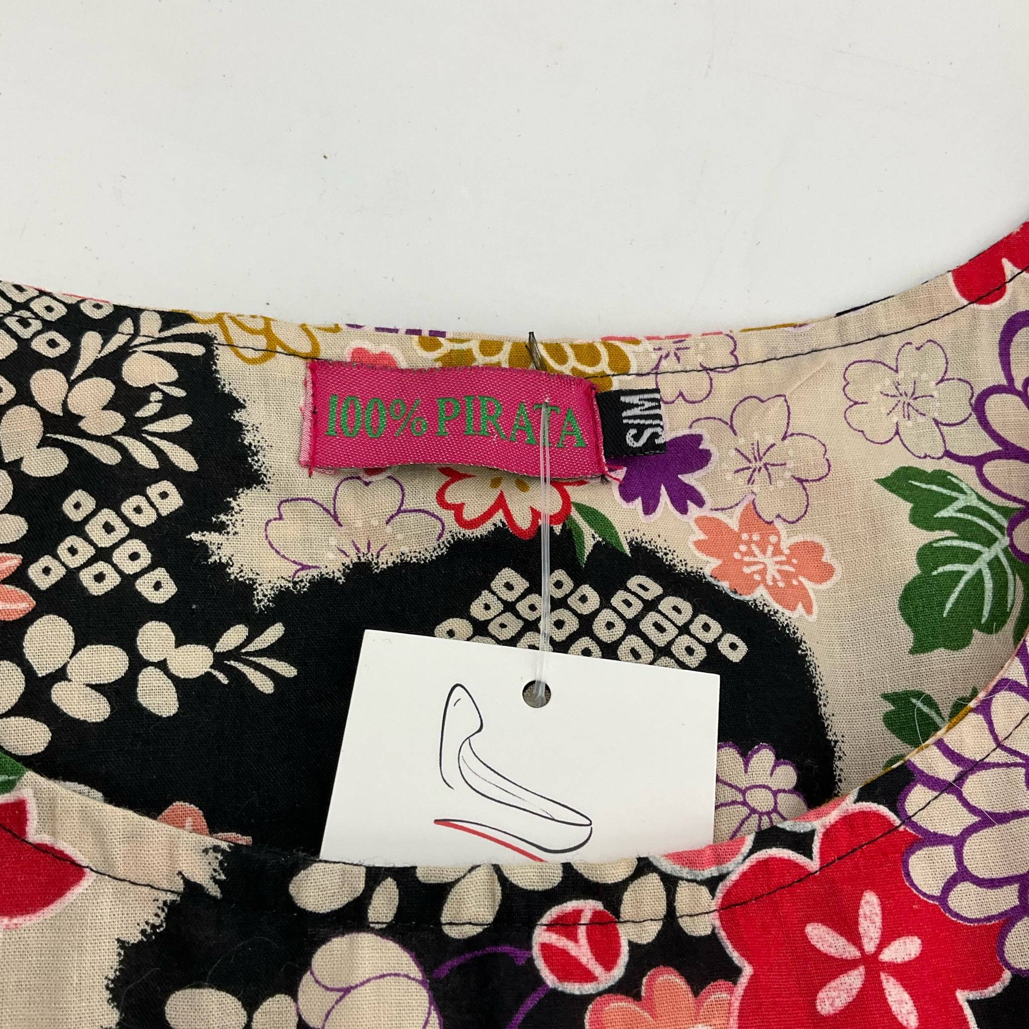 Close-up of 100% Pirata brand label on floral mini dress Size S/M, highlighting designer detail at Margaret’s Fine Consignments.