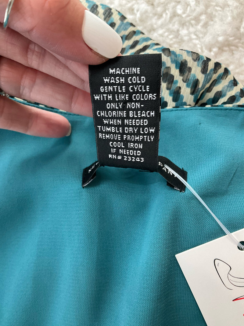 Care label of New York & Co teal/cream dress with washing instructions, emphasizing machine wash cold and tumble dry low settings.