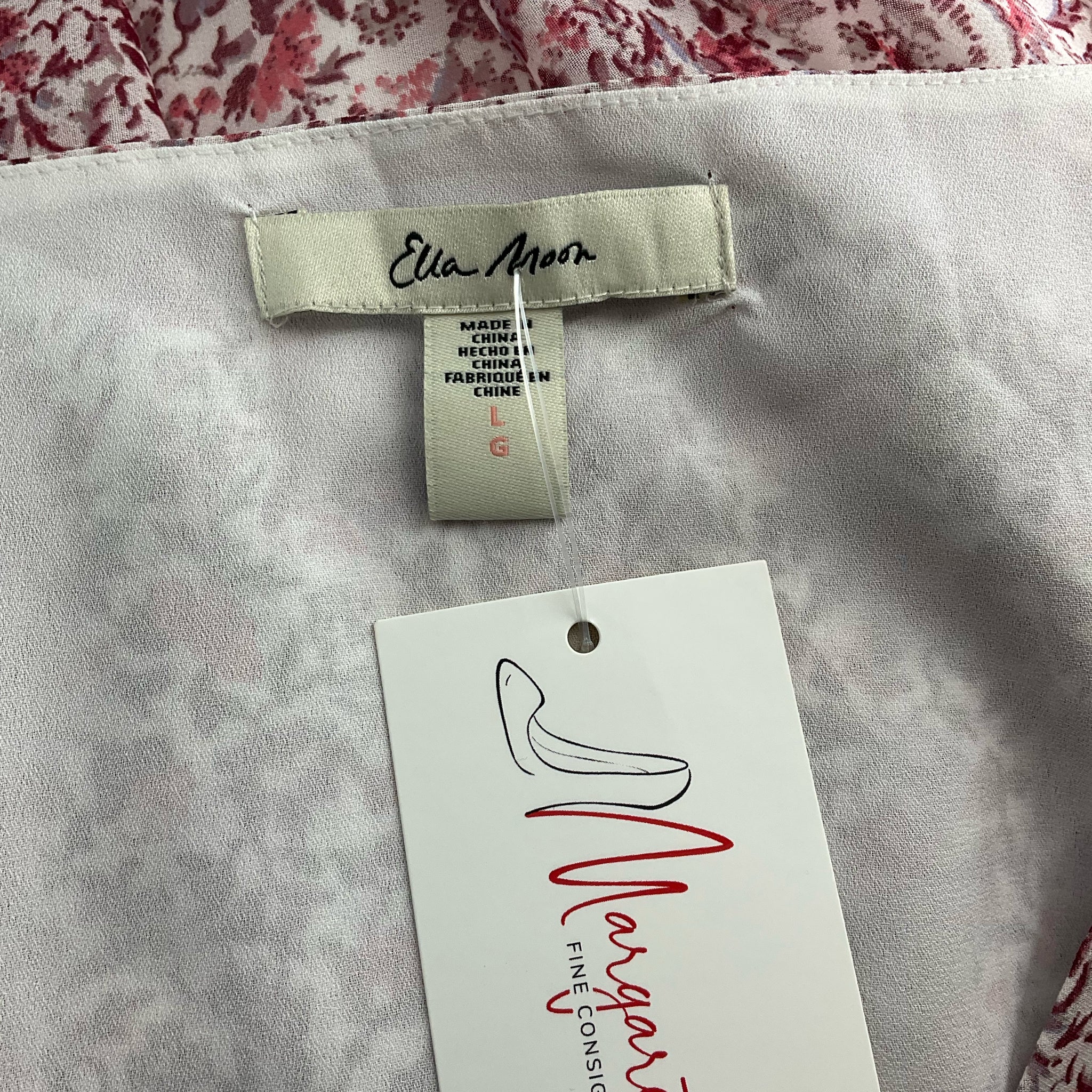 Close-up of Ella Moon brand label and size tag on Mauve/White Floral Maxi Dress - Size Large. Available at Margaret’s Fine Consignments.