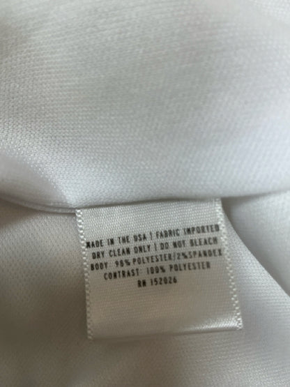 Close-up of fabric care label on Camilyn Beth white lace dress showing polyester-spandex blend and dry clean instructions.