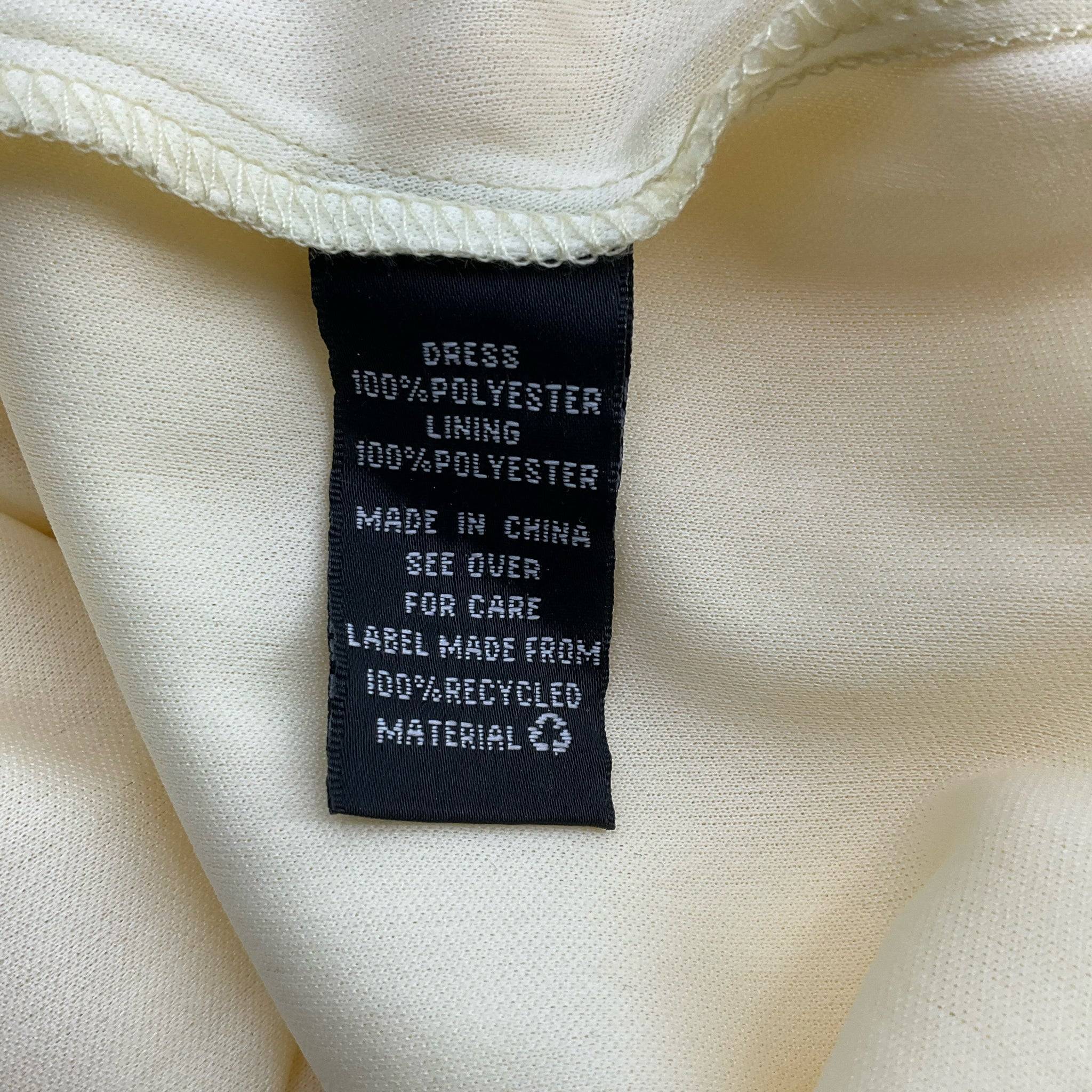 Close-up of BCX Dress Size Large care label showing 100% polyester fabric and lining, made from 100% recycled material.