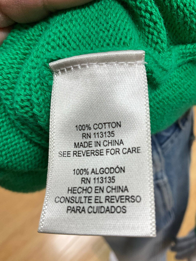 Fabric tag of Leo & Nicole green top showing 100% cotton material and care instructions, confirming quality at Margaret's Fine Consignments.