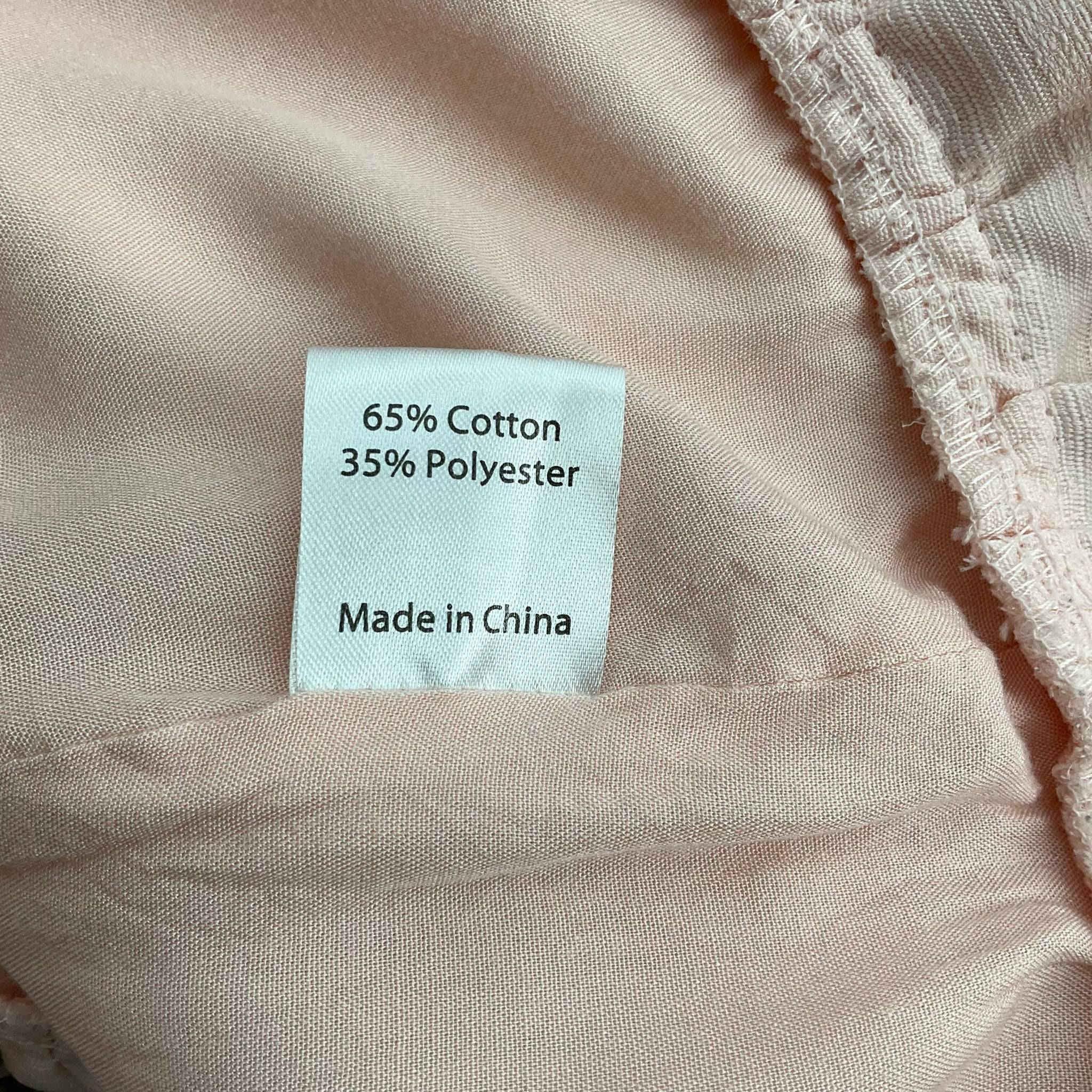 Fabric content tag of Princess Polly blush mini dress, 65% cotton and 35% polyester, available at Margaret’s Fine Consignments.