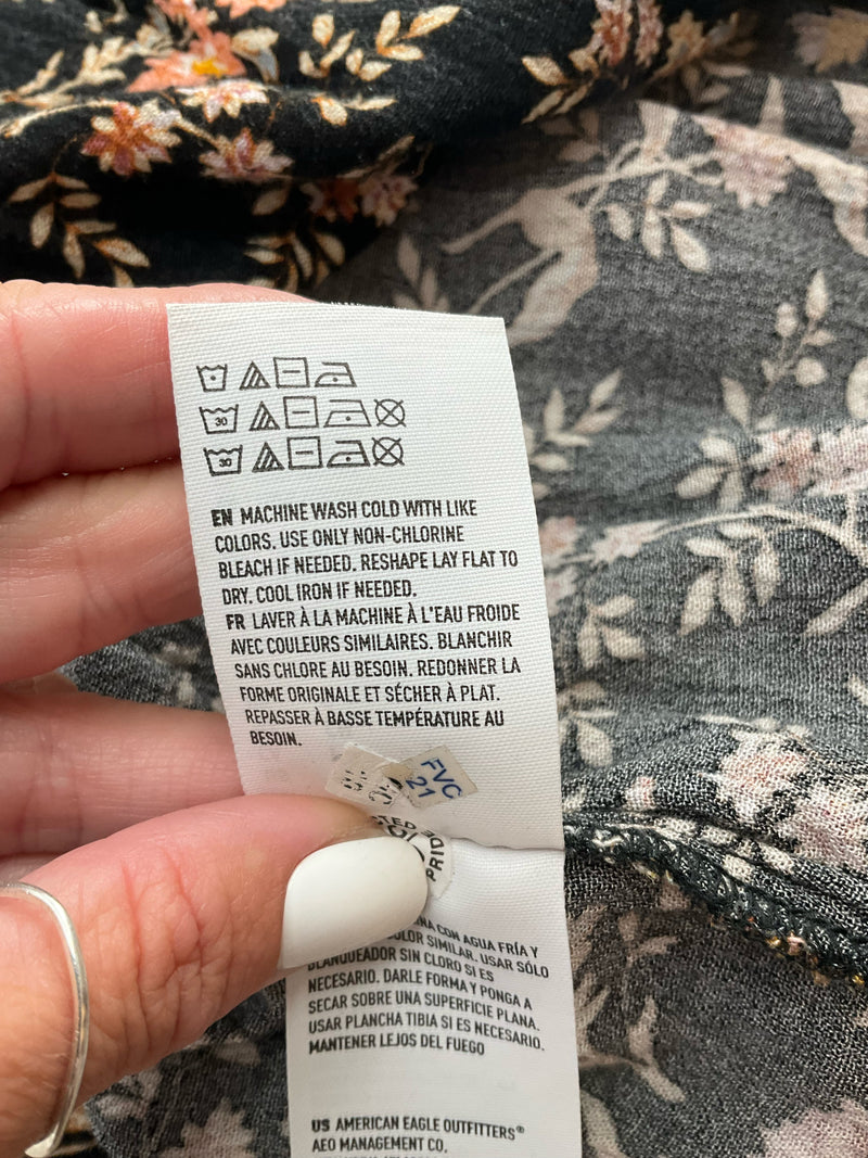 Care label for American Eagle floral cami top with washing instructions and multilingual text, confirming machine wash and flat dry.