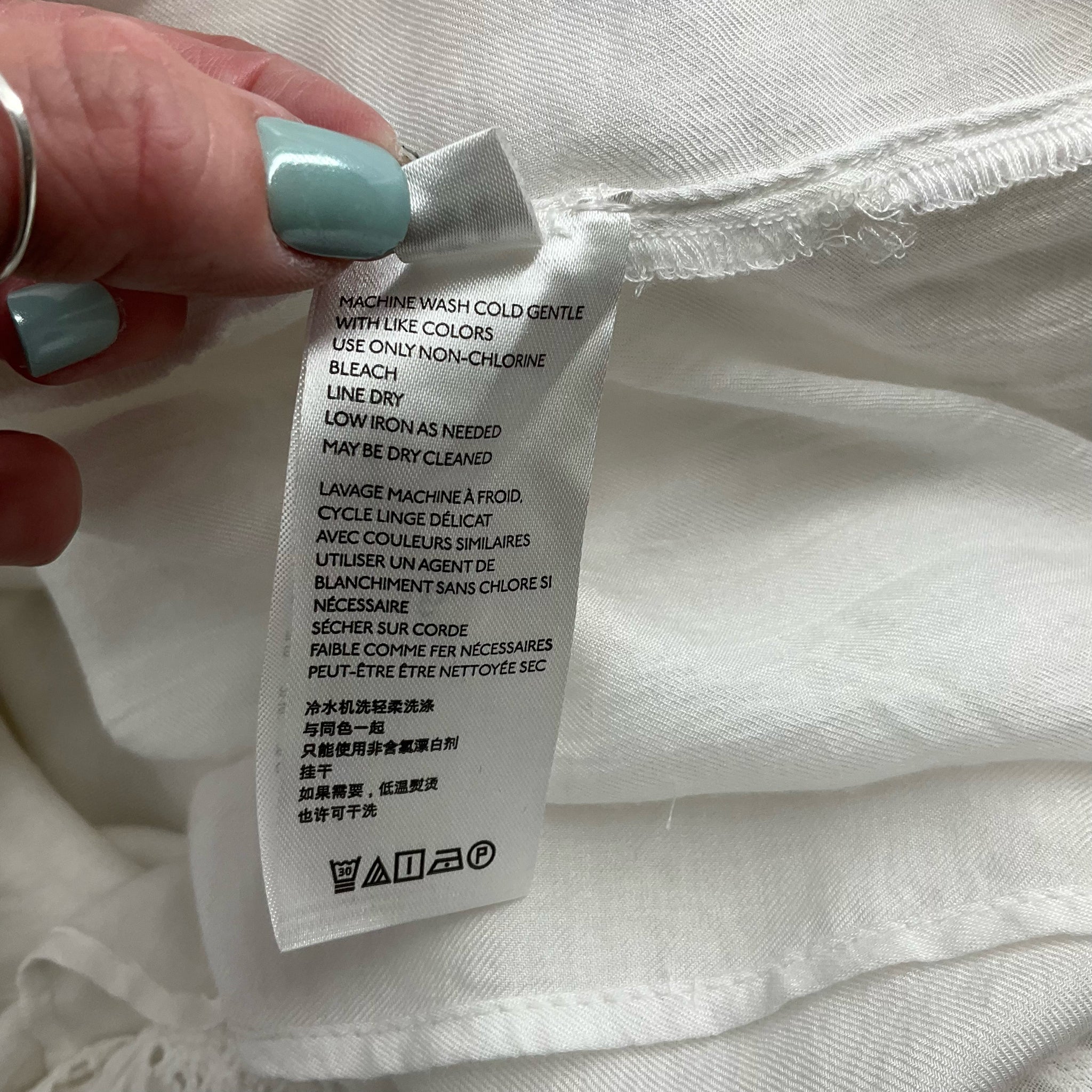 Care label on Anthropologie Maxi Dress - White Solid| Size 10 indicating machine wash cold and low iron instructions for easy maintenance.