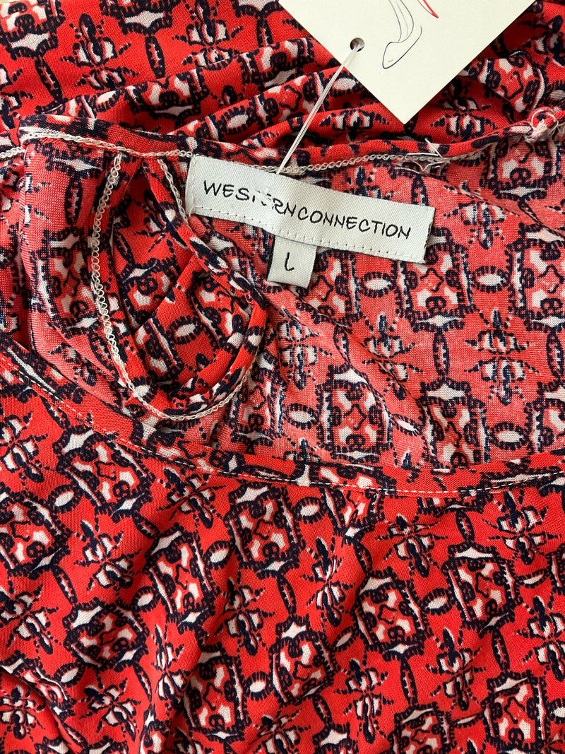 Close-up of Western Connection label on orange navy geometric print dress, size L, highlighting brand and keyhole neckline detail for easy wear.