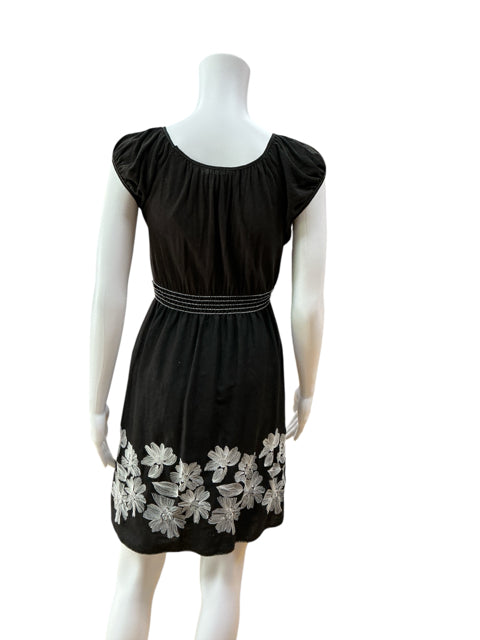 Back view of Studio M Black/White Floral Pre-Owned Ladies Dress - Size XS on mannequin. Shows smocked empire waist and floral embroidery near hem.